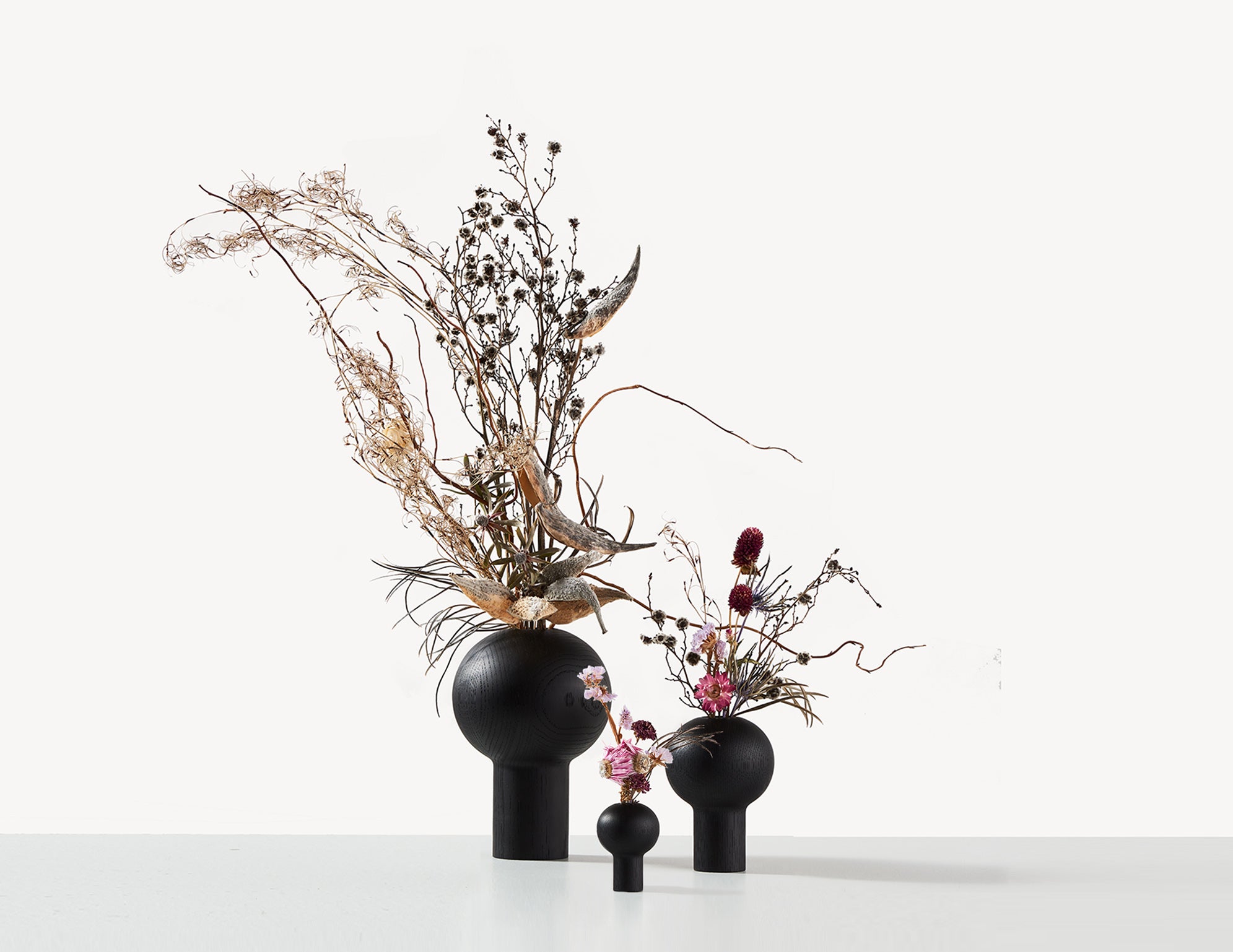 three black wooden vases with Ikebana flower arrangements.