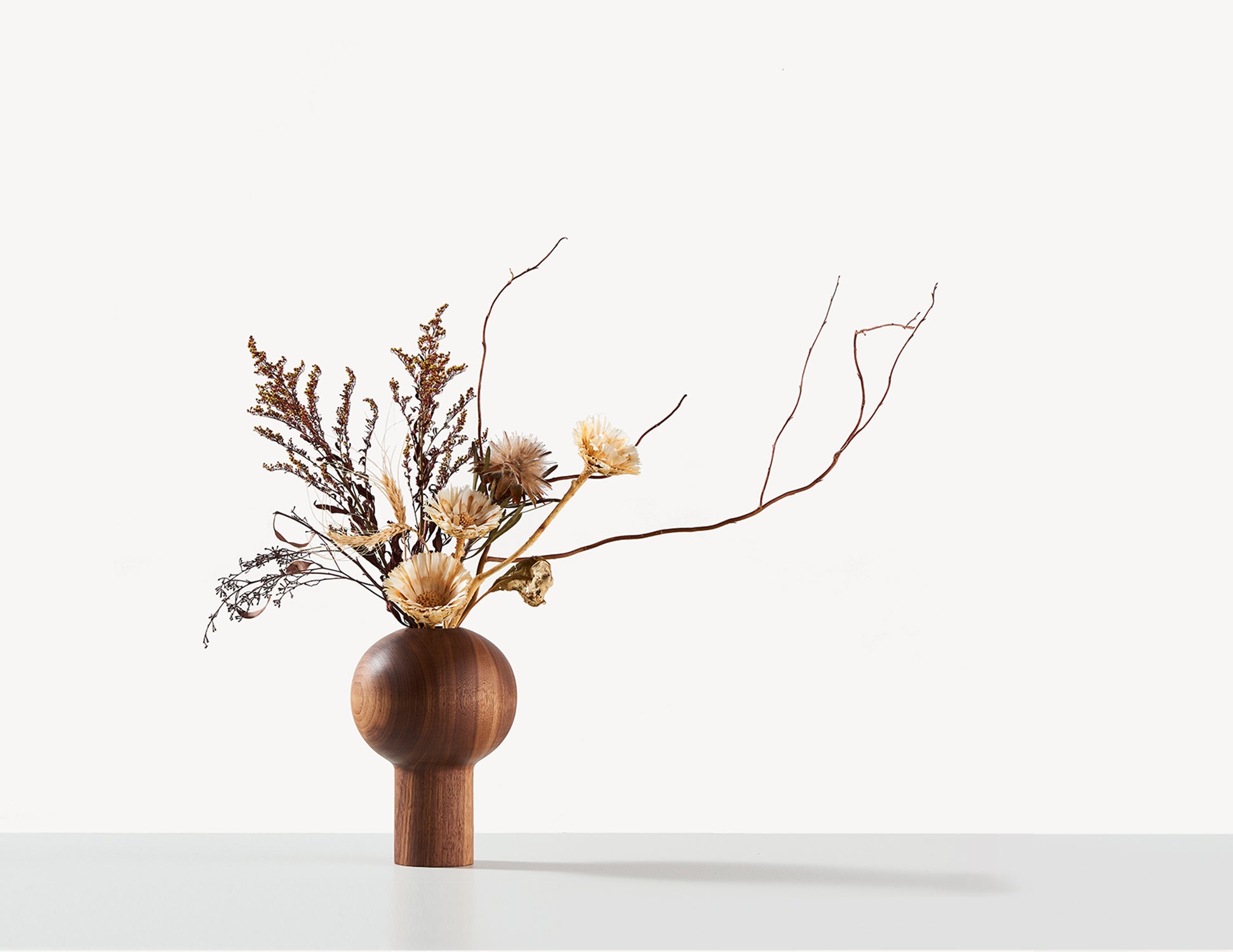 round wooden dry vase in walnut wood, with Ikebana flower arrangements.